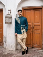 Royal teal blue Jacquard prince coat featuring intricate handmade golden embroidery, floral motifs, and a Mandarin collar, styled with a cream kurta pajama for a luxurious traditional wedding look.